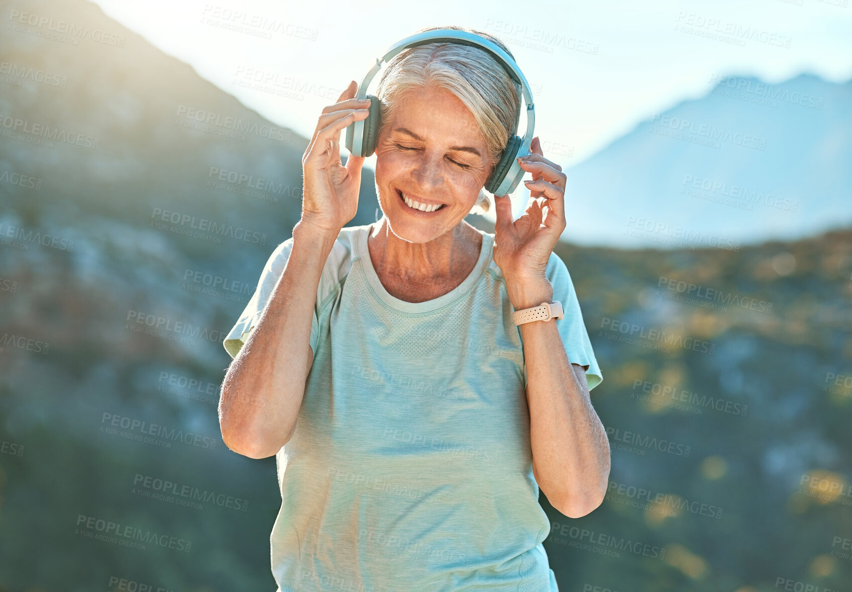 Buy stock photo Senior, happy woman and listening with headphones on mountain for music, peace or tranquility in nature. Mature, female person or yogi with smile or headset for outdoor freedom, zen or audio podcast