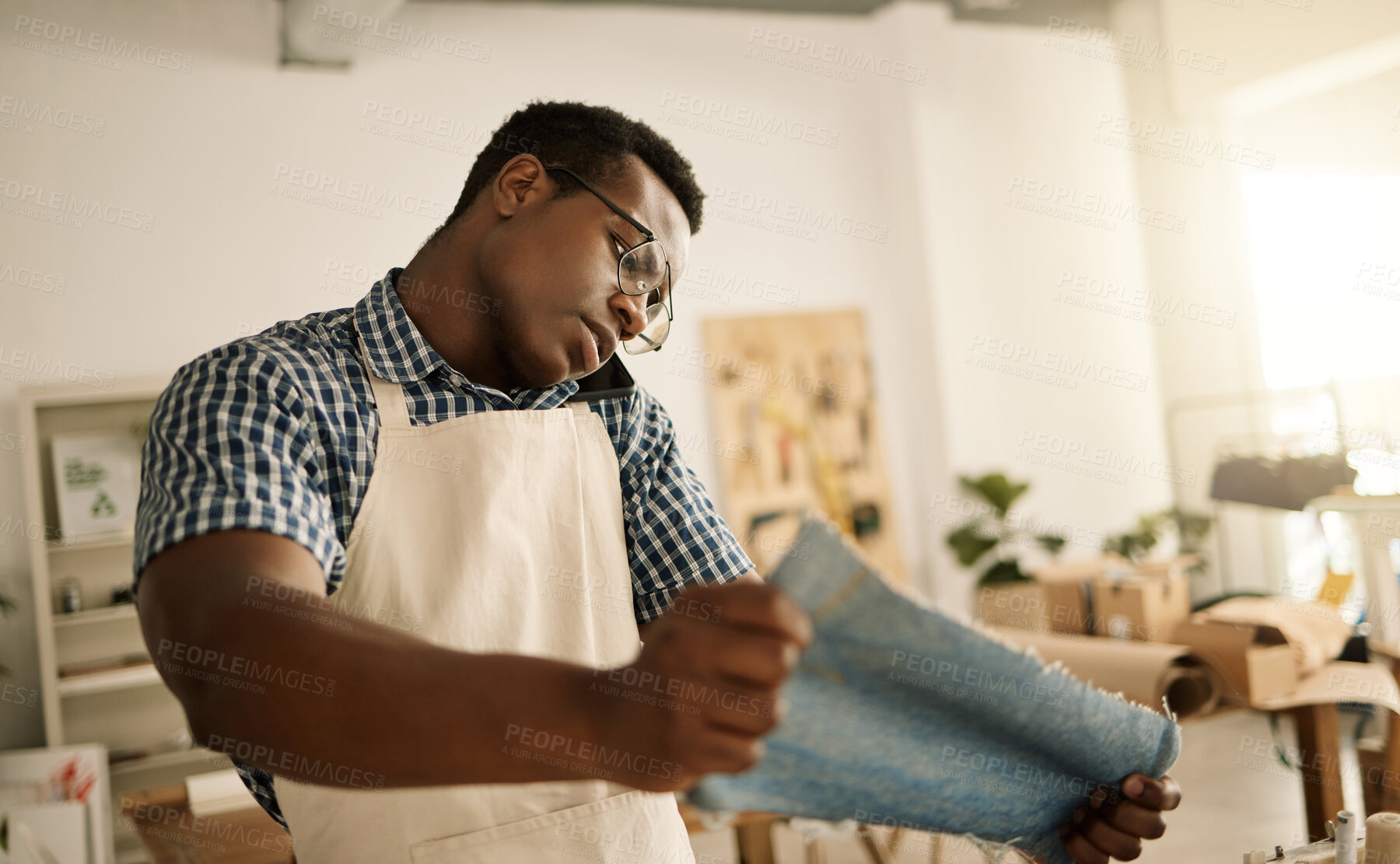 Buy stock photo Fashion designer, black man and talking with phone call at workshop for manufacturing or planning. Seamstress, client and startup with fabric material of denim for production, small business or order