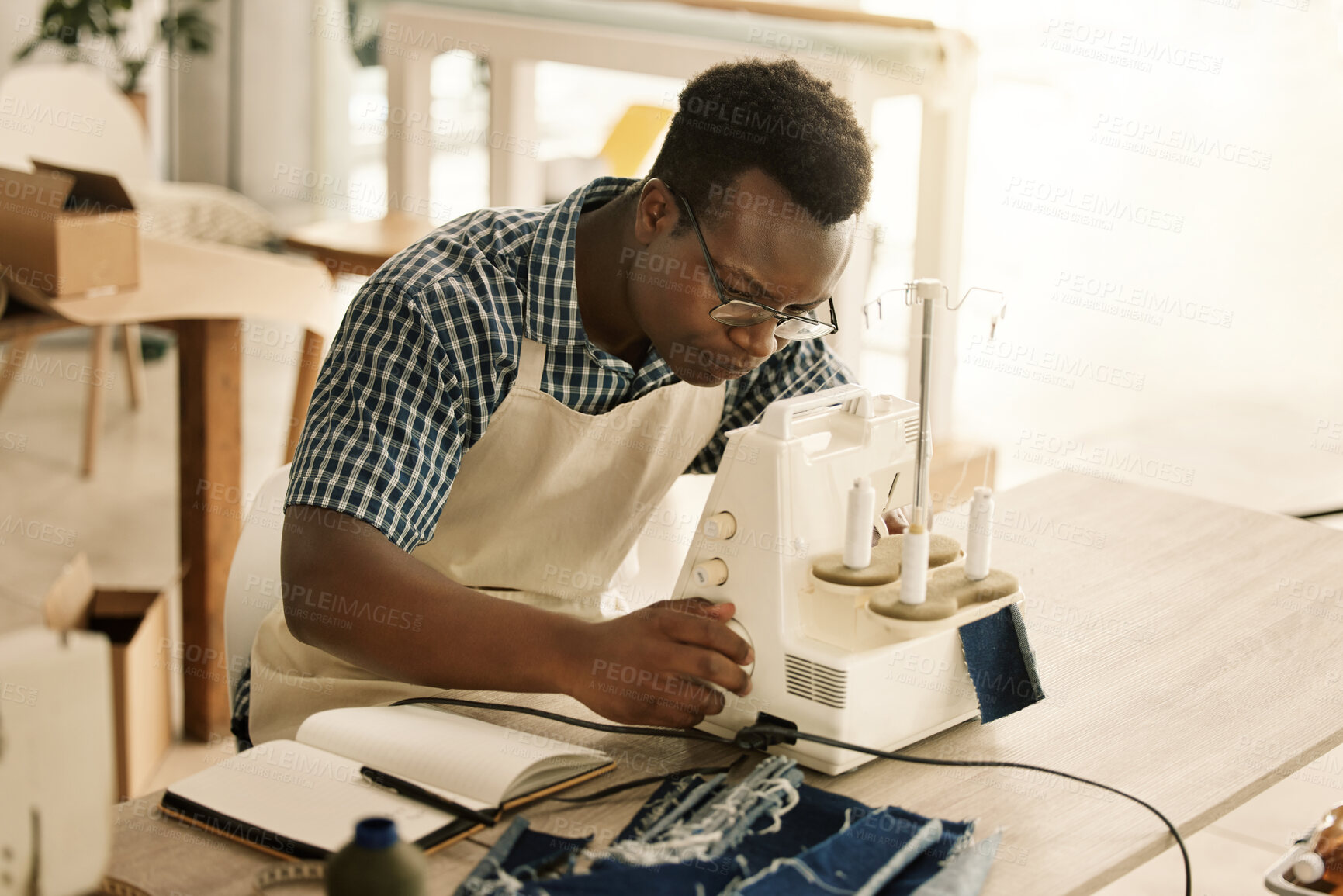 Buy stock photo Tailor, serious and man with sewing machine, working and thinking of design and threading of fabric. Seamstress, creative and black person in workshop, tailoring and dressmaker in factory and table