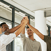 Smiling creative business team standing in office and giving high five ...