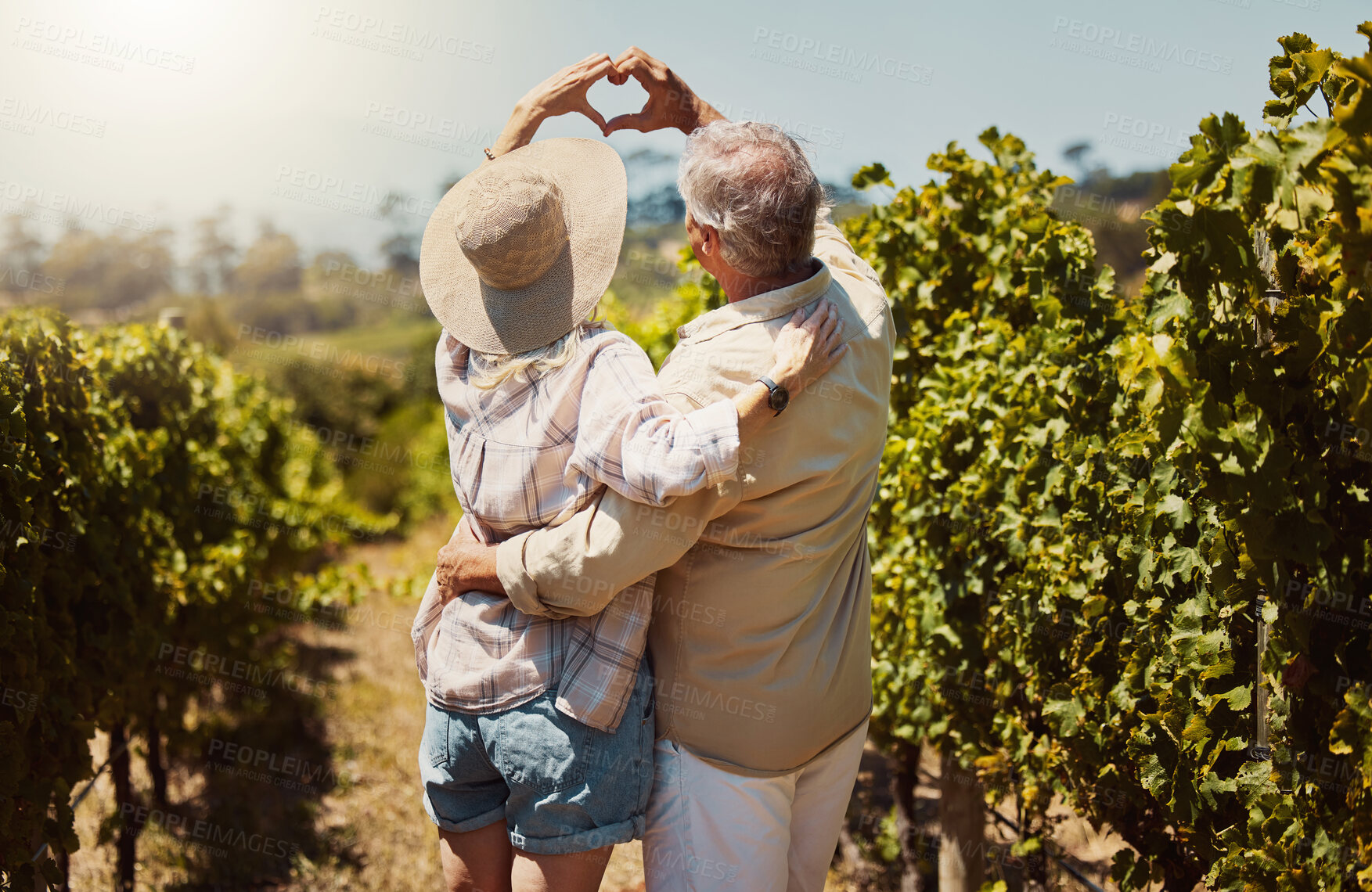 Buy stock photo Couple, back and love sign by nature for relationship, holiday and bonding together on date with hug. Mature, people and heart hands countryside farm for romance, vacation and embrace with sunshine