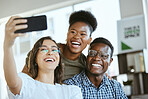 Group of young cheerful businesspeople taking a selfie together at work. Happy hispanic businesswoman taking a photo with her colleagues on her phone in an office