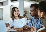 Three young happy businesspeople having a meeting while sitting at a table and working on a laptop at work. Business professionals talking and planning in an office together. Coworkers working on a business strategy