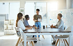 Group of diverse businesspeople having a meeting in an office at work. Young african american businesswoman holding a report and talking while doing a presentation at a table for coworkers. Businesspeople planning together