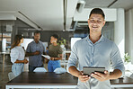 Portrait of a happy mixed race businessman working on a digital tablet in an office. Cheerful hispanic male businessperson holding and using social media on a digital tablet at work