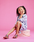 One cute little mixed race girl sitting in a studio and daydreaming against a pink copyspace background. A lonely African American child looking sad and depressed