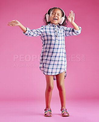 Buy stock photo Girl, child and singing with headphones in studio with dancing, excited and karaoke by pink background. Kid, happy and listening to music with streaming subscription for sound, smile and audio tech