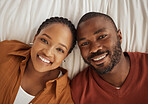 Portrait of a loving african american lying together on a bed, from above. Happy young man and woman smiling and looking at camera