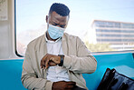 Black businessman travelling alone. A young african american businessman sitting on a seat while sitting at the window on a train and wearing a mask during his commute to the city