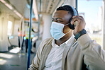 Black businessman travelling alone. A young african american businessman  listening to music on his wireless headphone while sitting at the window on a train during his commute to the city