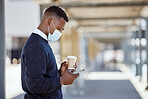 Black businessman travelling alone. A young african american businessman waiting for a train at a railway station and using his wireless cellphone during his commute at a train station