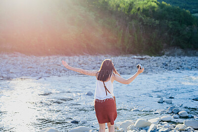 Buy stock photo Back, woman and camera in river for travel, journey and summer adventure in nature. Girl, digital tech and balance at water for crossing, wilderness vacation or freedom in environment for photography