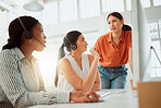 Young hispanic call centre telemarketing agent training new assistants on a computer in an office. Team leader troubleshooting solution with interns for customer service and sales support. Colleagues operating helpdesk together