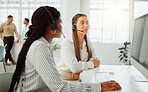 Young hispanic call centre telemarketing agent discussing plans with a colleague while working together on a computer in an office. Consultants troubleshooting solution for customer service and sales support