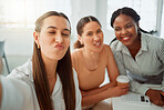 Portrait of a confident young hispanic business woman making a funny face expression while taking selfies with her colleagues in an office. Group of three happy smiling women taking photos as a dedicated and ambitious team in a creative startup agency