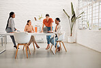 Diverse group of businesswomen having a meeting together in a boardroom at work. Serious businesspeople talking while planning and using a laptop in a workshop in an office