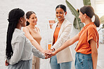 Group of happy businesswomen stacking their hands together in an office at work. Diverse group of cheerful businesspeople having fun standing with their hands stacked in unity