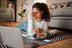 Stressed young woman using her laptop. Young woman experiencing a headache in front of her computer. Laptop issues always happen at home. Woman lying on her floor looking worried