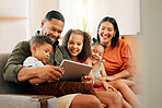 A happy mixed race family of five relaxing on the sofa at home. Loving black family being affectionate on the sofa while using a digital tablet and streaming. Young couple bonding with their kids and watching movies at home