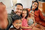 Portrait of a mixed race family of five relaxing on the sofa at home. Loving black family taking a selfie on the sofa. Young couple bonding with their adopted kids at home