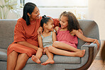 A happy mixed race family of three relaxing in the lounge and sitting on the couch together. Loving black single parent bonding with her daughters while relaxing on a sofa at home