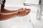 An unknown mixed race child washing their hands in a bathroom at home. Unrecognizable Hispanic child with healthy daily habits to prevent the spread of germs and illness