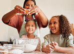 Females only, happy mixed race family of three cooking in a messy kitchen together. Loving black single parent bonding with her daughters while teaching them domestic skills at home