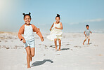 Cheerful energetic little girl running and playing at the beach with her siblings following in the background.  Happy kids having a race on the beach