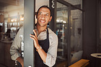 Business owner opening his restaurant door. Mixed race businessman waiting for customers in his coffeeshop. Store owner standing in his entrance. Cafe assistant standing by the shop door.