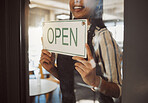 Closeup on hands of business owner hanging open sign. Businesswoman hanging signage in her store door. Hands of boss advertising that her shop is open. Manager hanging message that the cafe is open