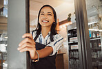 Business owner waiting for customers in her shop entrance. Young businesswoman standing at her coffeeshop door. Happy boss standing in grocery store entrance. Customers known we're ready for business