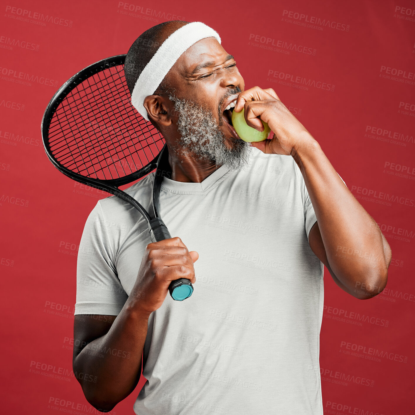 Buy stock photo Racket, mature and black man in studio with apple, nutrition and wellness with vitamin c for sports. Male person, tennis player and bite with fruit for heart health, fitness game and red background