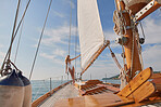 Blonde woman in white swimsuit holding yachts sail enjoying the sun. Young woman in white swimsuit on yacht cruise holding yacht sail. Young woman enjoying the sun on a yacht cruise holding boat sail