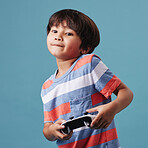 Young mixed race boy standing and holding a console controller while playing a video game against a blue background. Fun and games are a good activity for weekends