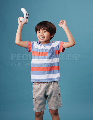 Buy stock photo Boy, controller and gamer for celebration in studio, winner and esports success or triumph. Male person, kid streaming and console for playing on blue background, arcade competition and achievement