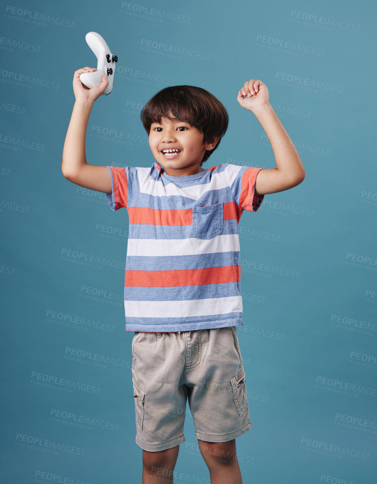 Buy stock photo Boy, controller and gamer for celebration in studio, winner and esports success or triumph. Male person, kid streaming and console for playing on blue background, arcade competition and achievement