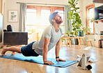 One fit young caucasian man doing cobra push up bodyweight exercise while training with online tutorial on digital tablet at home. Focused guy challenging himself to gain muscle, core strength and increase endurance during yoga workout