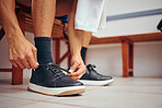 Squash player tying his shoe laces in his gym locker room. Hand of a mixed race player preparing for a match. Closeup of squash player tying the laces of his sport sneaker in the locker room