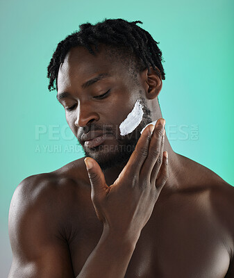 Buy stock photo Black man with shaving cream, skincare product on face in studio background and smooth facial hair. Young african model grooming, male hygiene and cleaning beard with cosmetic morning routine