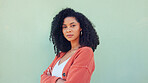 Woman, confident beauty and young model pose for portrait with afro hair on green background. African girl in orange sweater, fold arms with cool serious face and casual fashion lifestyle