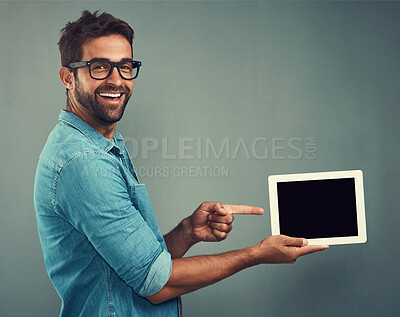 Buy stock photo Happy man, tablet and pointing to mockup screen for advertising against a grey studio background. Portrait of male person smiling showing technology display, chromakey or copy space for advertisement