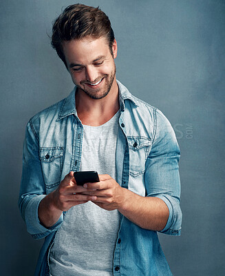 Buy stock photo Studio, reading and man with phone, smile and funny message, texting and online in social media of app. Blue background, happy and person with mobile, typing and connection for communication in web