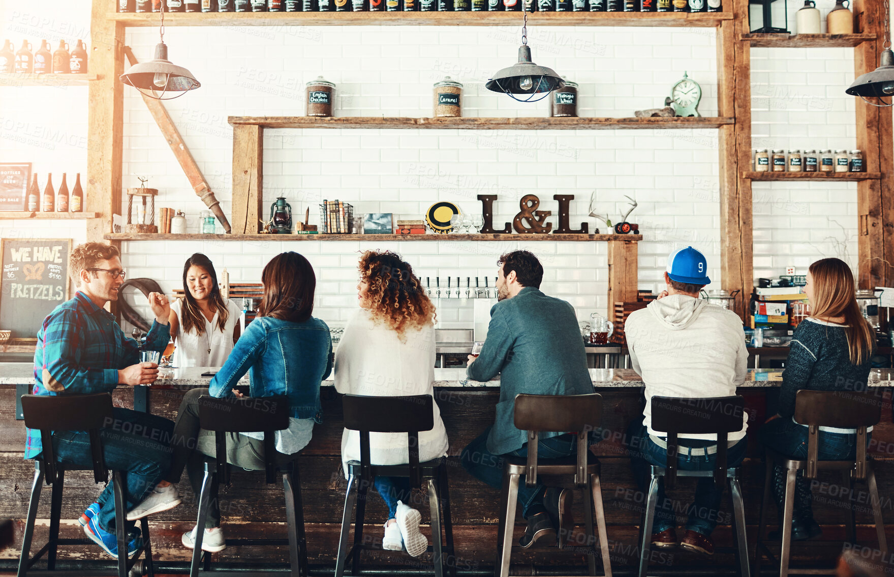 Buy stock photo Rearview shot of people drinking at a bar