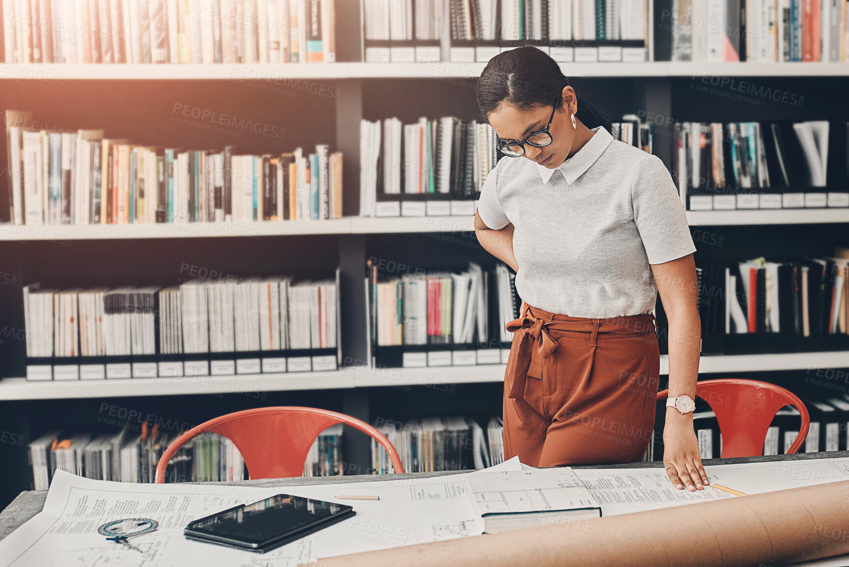 Buy stock photo Cropped shot of an attractive young female architect working with blueprints in a modern office