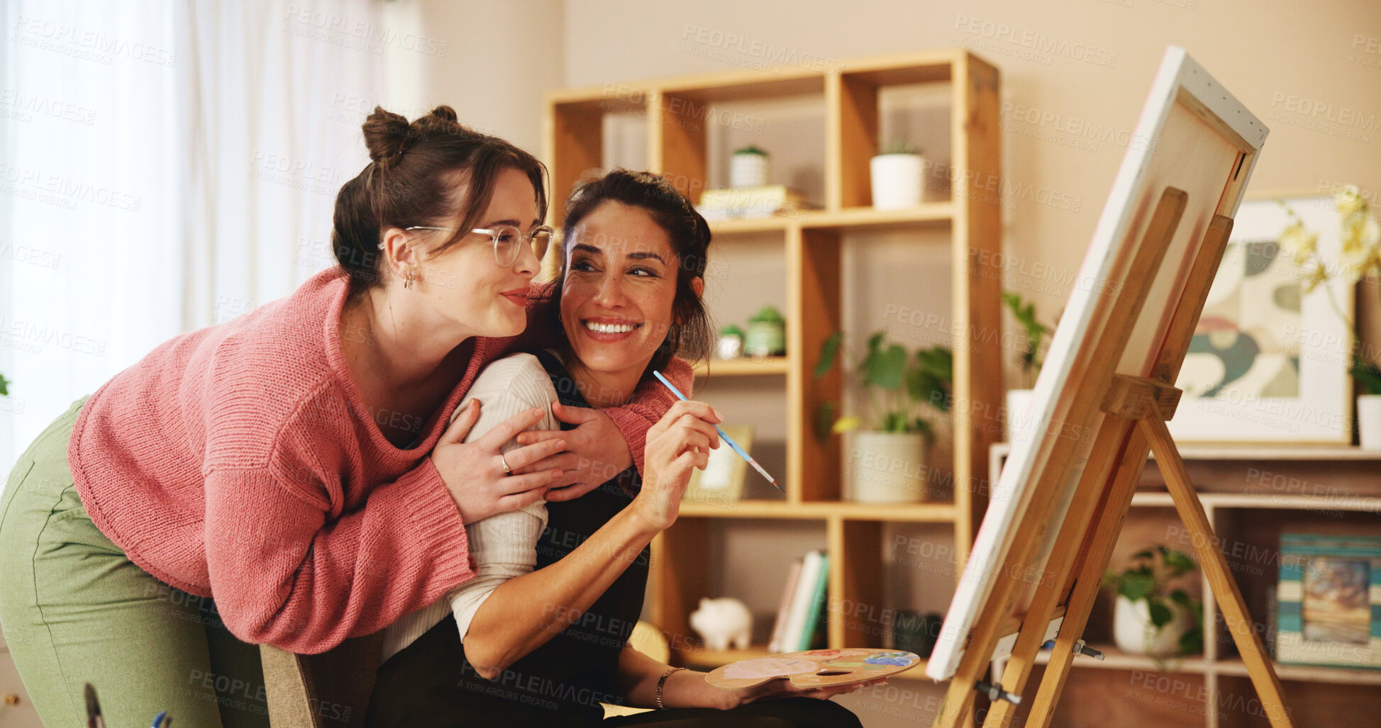 Buy stock photo Lesbian, couple and painting with canvas in home for design project, help and hobby on weekend. Happy, LGBTQ and women with hug by easel in house for love, support and discussion on creative artwork