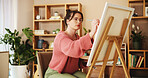 Art, painting and woman with paintbrush in studio for creative artwork, drawing and design with canvas. Hobby, artistic skill and person with easel in home for inspiration, project and illustration