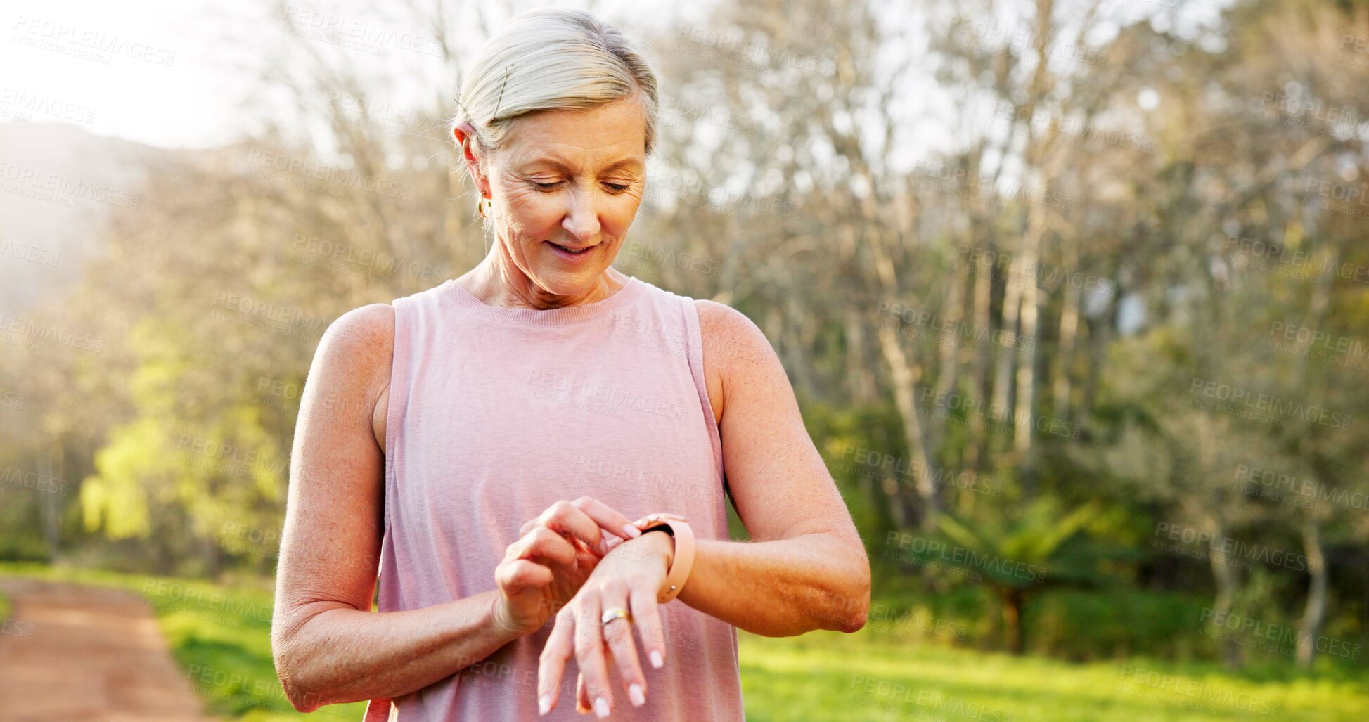 Buy stock photo Mature, woman and check smart watch in nature for running performance, tracking speed and fitness monitor. Person, runner and biometric in forest for wellness progress, heart rate and workout outdoor