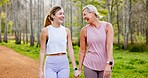 Mother, daughter and holding hands in forest with hiking for fitness adventure, sightseeing or laughing. Bonding, mature woman or girl in woods with walking, holiday travel or talking on outdoor path