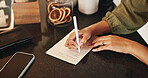 Hands, women and writing on paper for shopping list, planning and groceries for household. Female person, housewife and home on kitchen counter or desk for house items, checklist and reminder