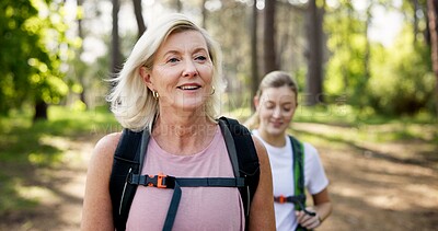 Buy stock photo Mother, daughter and hiking in forest with backpack for fitness adventure, sightseeing and explore nature. Trekking, happy mature woman and girl in woods with walking, holiday travel and cardio hobby